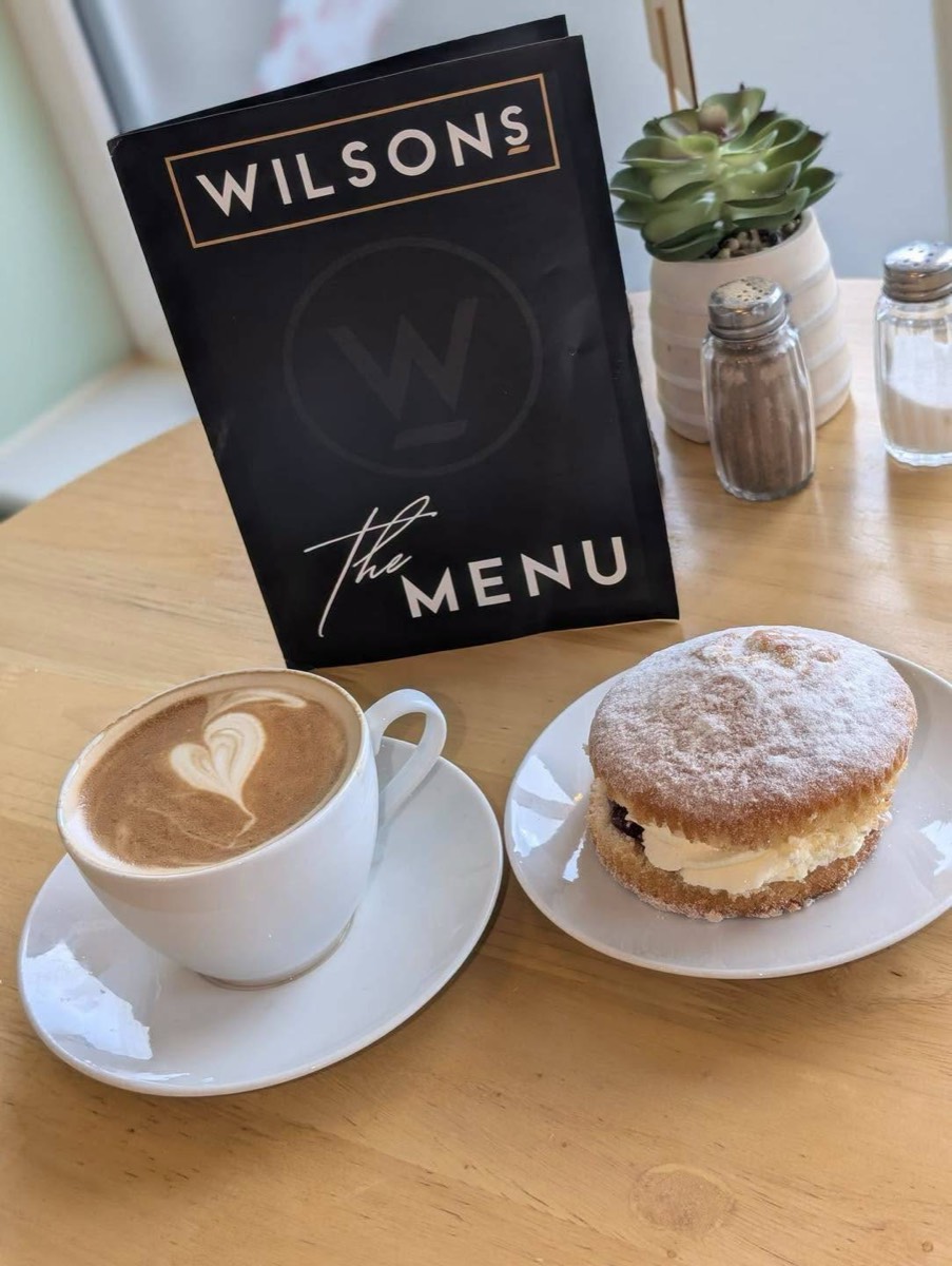 Latte and a cake next to the Wilson's menu