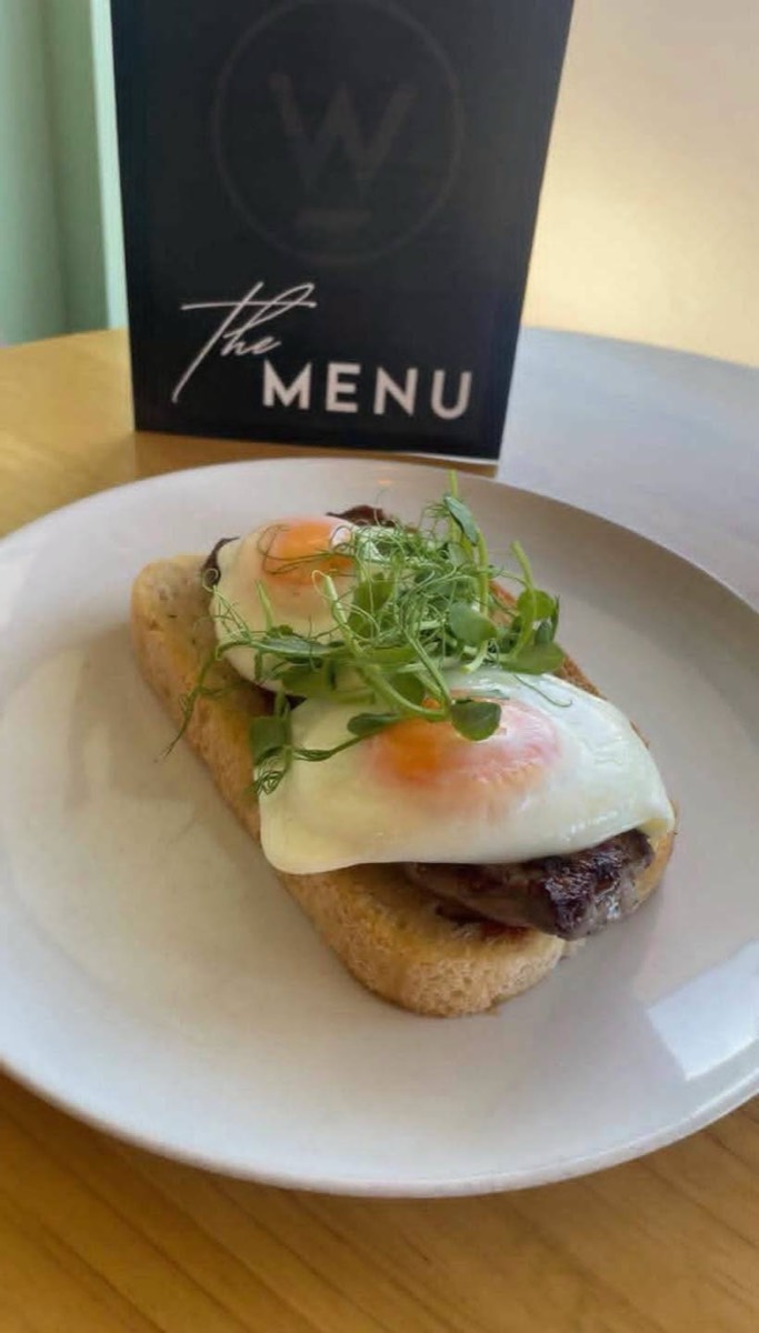 Fried egg and greens on toast next to the menu